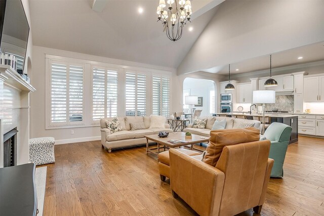 2717 River Path Ct, Burleson, TX 76028 - living area with arched walkways, high vaulted ceiling, a chandelier, a fireplace, and light wood-style flooring