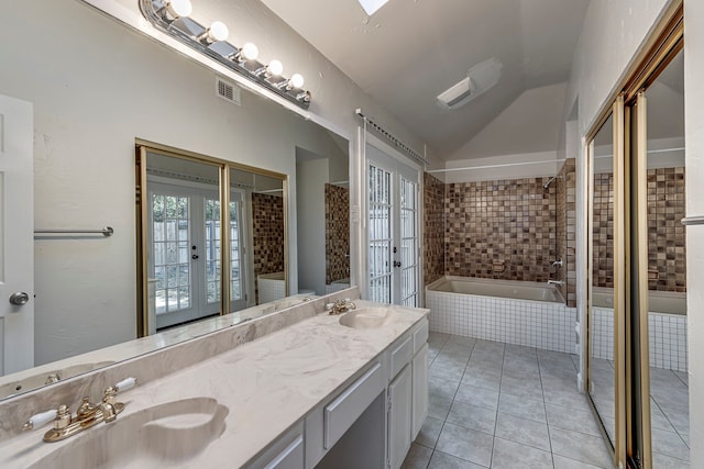 bathroom featuring vanity, french doors, tile patterned floors, vaulted ceiling, and tiled tub