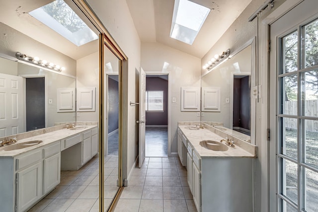 bathroom featuring vanity, tile patterned floors, and vaulted ceiling with skylight