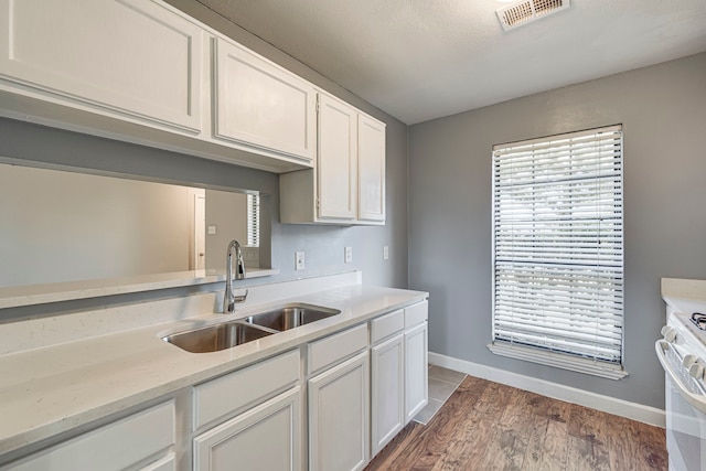 kitchen with dark wood-type flooring, white cabinets, white range with electric cooktop, sink, and a textured ceiling