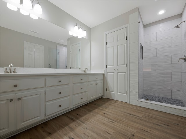 bathroom with hardwood / wood-style floors, vanity, and tiled shower