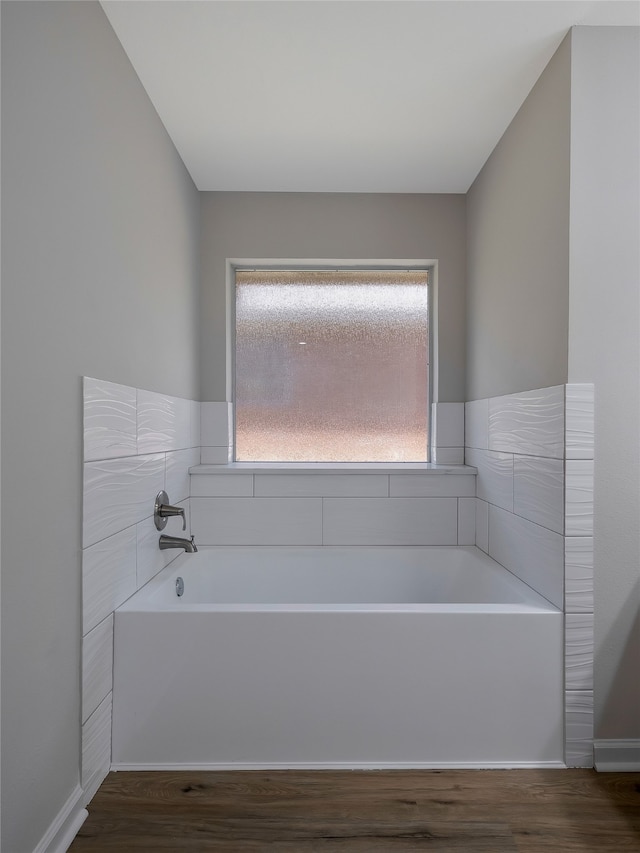 bathroom featuring plenty of natural light, wood-type flooring, and a washtub