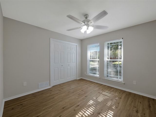 unfurnished bedroom with ceiling fan, a closet, and light wood-type flooring