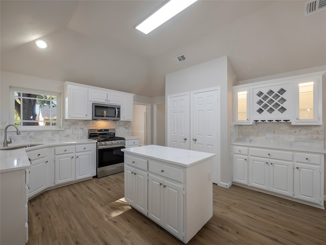 kitchen featuring a center island, sink, stainless steel appliances, backsplash, and white cabinets