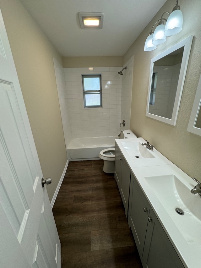 full bathroom with vanity, hardwood / wood-style flooring, toilet, and tiled shower / bath