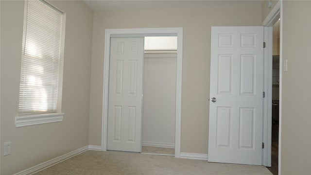 unfurnished bedroom featuring light colored carpet and a closet