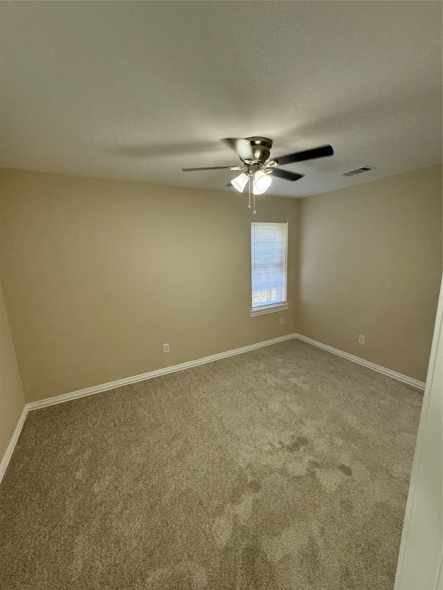 carpeted spare room featuring ceiling fan and a textured ceiling