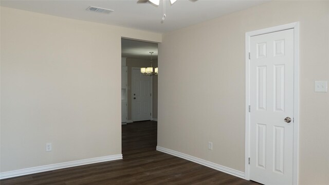 empty room featuring ceiling fan with notable chandelier and dark wood-type flooring