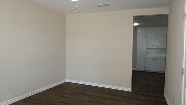 spare room with dark hardwood / wood-style floors and ceiling fan