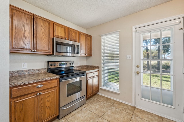 kitchen featuring plenty of natural light, light tile patterned floors, a textured ceiling, and appliances with stainless steel finishes