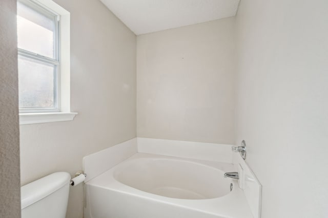 bathroom with a bathing tub, toilet, and a textured ceiling