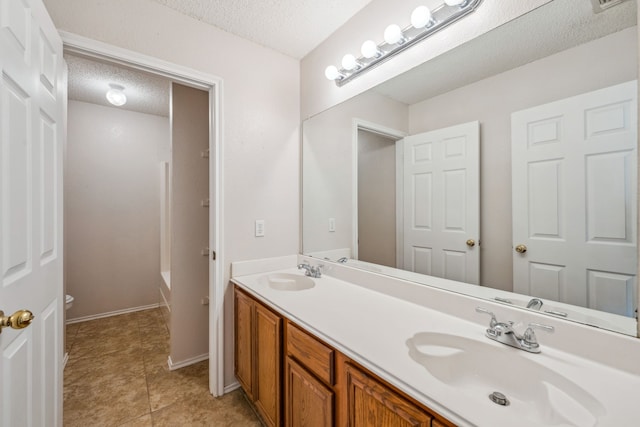 bathroom featuring a washtub, tile patterned floors, a textured ceiling, toilet, and vanity