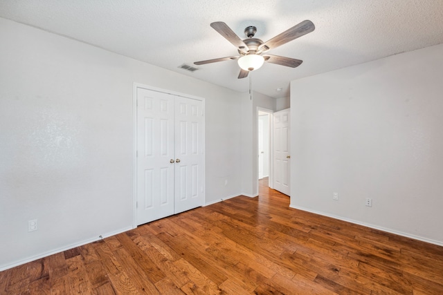 unfurnished bedroom featuring wood-type flooring, a textured ceiling, and ceiling fan