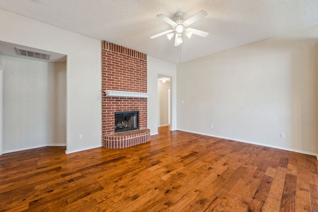 unfurnished living room with hardwood / wood-style floors, a fireplace, and a textured ceiling