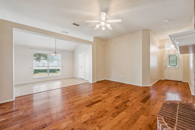 unfurnished room featuring hardwood / wood-style flooring, ceiling fan with notable chandelier, lofted ceiling, and a textured ceiling