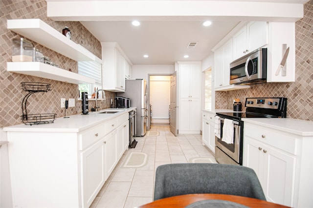 kitchen featuring sink, decorative backsplash, light tile patterned floors, appliances with stainless steel finishes, and white cabinetry