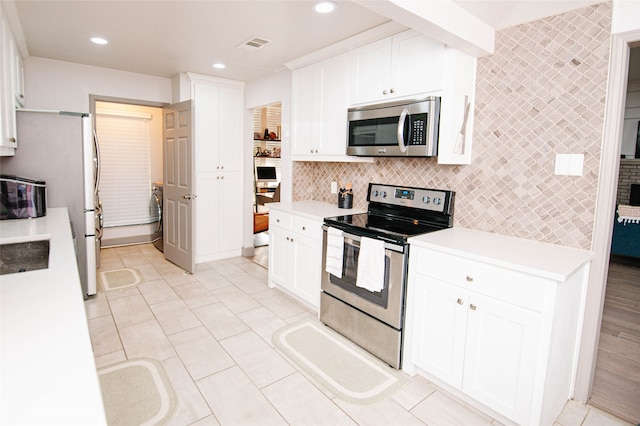 kitchen with white cabinets, light tile patterned floors, stainless steel appliances, and tasteful backsplash