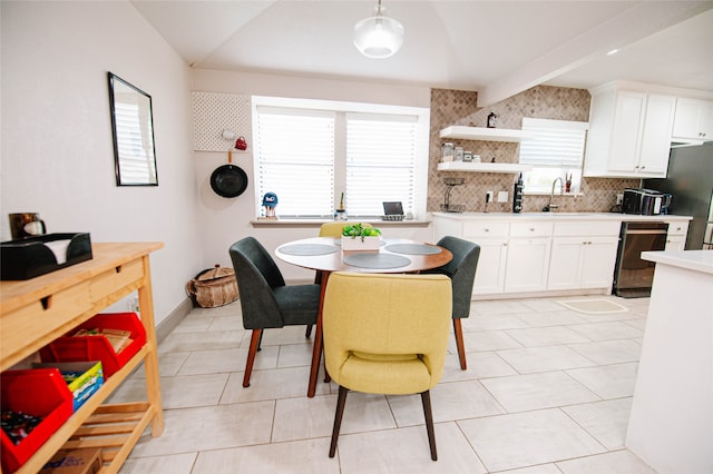 dining area featuring beamed ceiling, light tile patterned floors, and sink