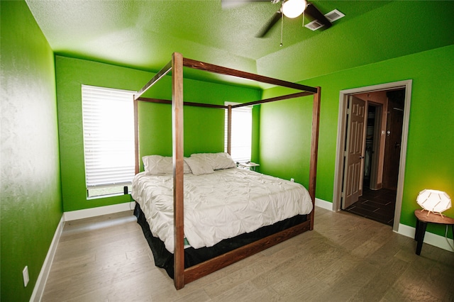 bedroom featuring a textured ceiling, hardwood / wood-style flooring, ensuite bath, and ceiling fan