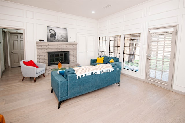 living room with a fireplace, light hardwood / wood-style flooring, and ornamental molding