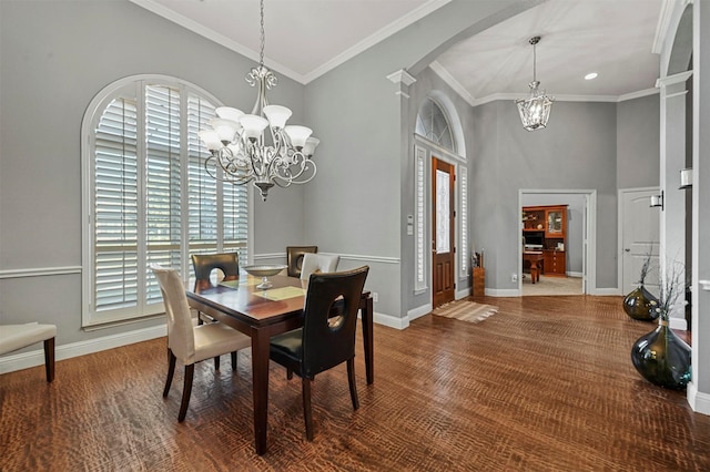 dining area featuring an inviting chandelier, baseboards, arched walkways, and crown molding