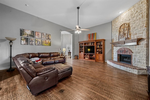 living area with a ceiling fan, arched walkways, a fireplace, and baseboards