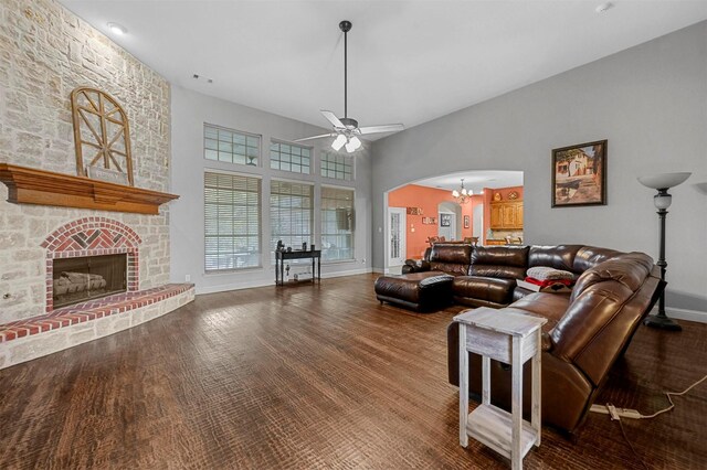 living room featuring a large fireplace, baseboards, visible vents, arched walkways, and ceiling fan with notable chandelier