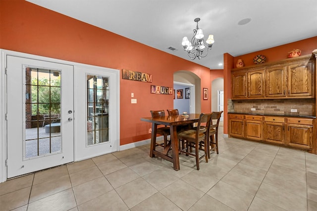 dining area with visible vents, arched walkways, french doors, a notable chandelier, and light tile patterned flooring