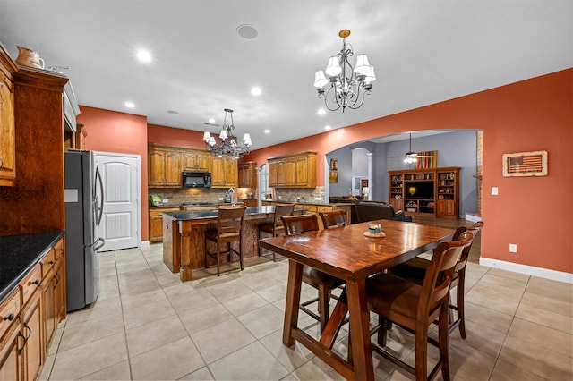 dining area featuring arched walkways, light tile patterned floors, recessed lighting, baseboards, and ceiling fan with notable chandelier