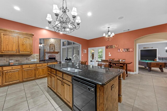 kitchen with a sink, brown cabinetry, dishwasher, an island with sink, and pendant lighting