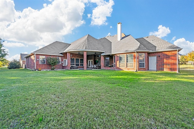 back of property with a yard, a chimney, and brick siding