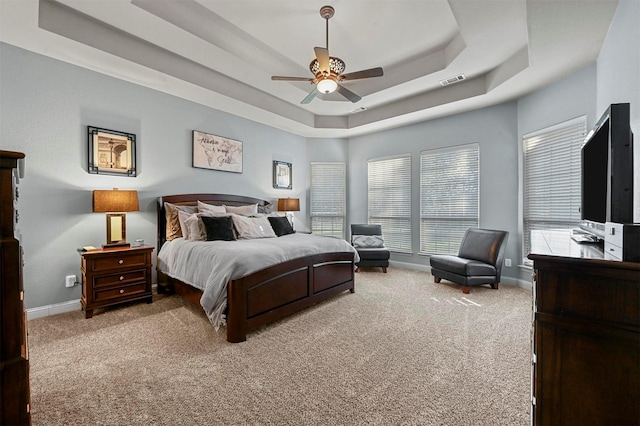 bedroom featuring light carpet, visible vents, baseboards, and a raised ceiling