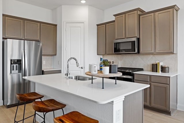 kitchen with a center island with sink, sink, appliances with stainless steel finishes, and tasteful backsplash