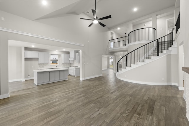 unfurnished living room featuring hardwood / wood-style floors, ceiling fan, beamed ceiling, and high vaulted ceiling