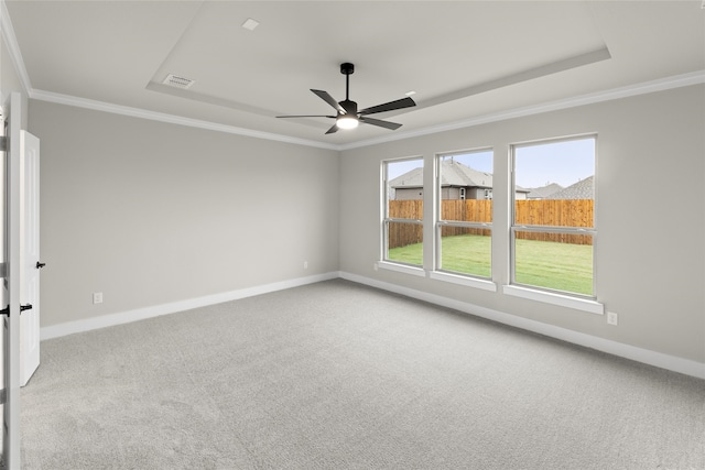 carpeted empty room with a tray ceiling, ceiling fan, and crown molding