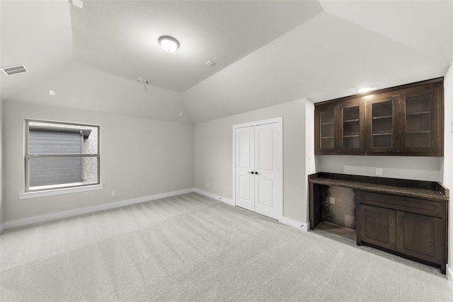 additional living space with light colored carpet and vaulted ceiling