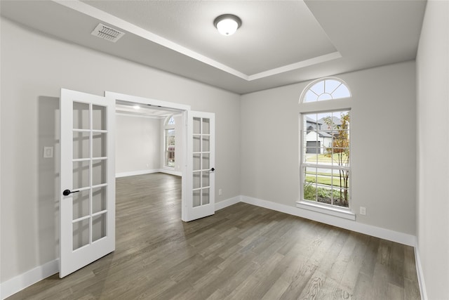 unfurnished room with hardwood / wood-style floors, a tray ceiling, and french doors