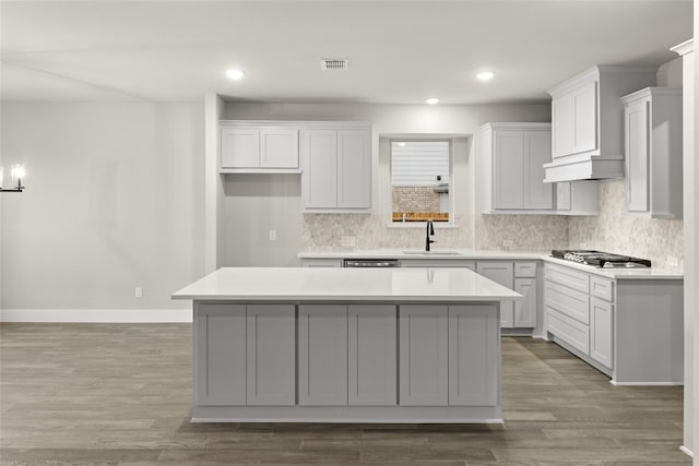 kitchen featuring light wood-type flooring, a kitchen island, stainless steel gas stovetop, and sink