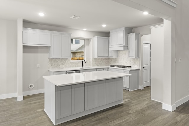 724 Stearman Ln, Fate, TX 75087 - kitchen with appliances with stainless steel finishes, decorative backsplash, a kitchen island, wood finished floors, and light countertops