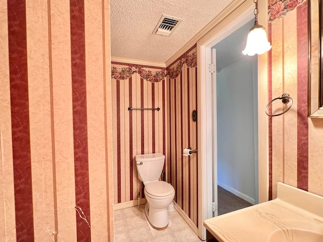 bathroom featuring crown molding, toilet, and a textured ceiling