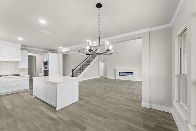 kitchen featuring gas cooktop, pendant lighting, hardwood / wood-style floors, a center island, and white cabinetry