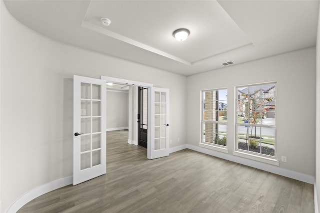 unfurnished room featuring a tray ceiling, french doors, and hardwood / wood-style floors