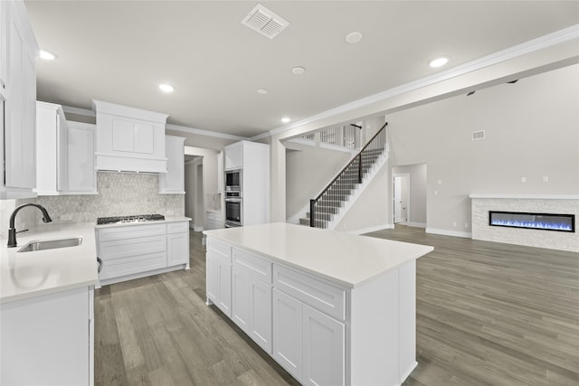 kitchen featuring a center island, sink, stainless steel appliances, light hardwood / wood-style flooring, and white cabinets