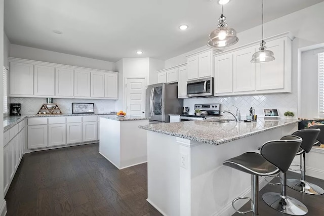 kitchen featuring white cabinets, a kitchen island, dark wood-type flooring, and appliances with stainless steel finishes