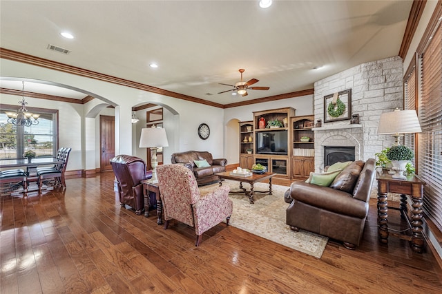 living room with ceiling fan, a stone fireplace, hardwood / wood-style floors, a textured ceiling, and ornamental molding