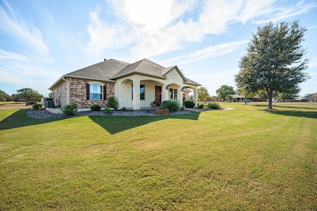 view of front of home with a front lawn, covered porch, and central AC unit