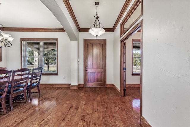 entryway featuring plenty of natural light, an inviting chandelier, ornamental molding, and hardwood / wood-style flooring