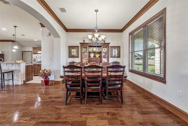 dining space featuring dark hardwood / wood-style flooring, ornamental molding, and a chandelier