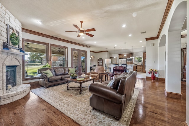 living room featuring hardwood / wood-style flooring, ceiling fan with notable chandelier, ornamental molding, and a fireplace