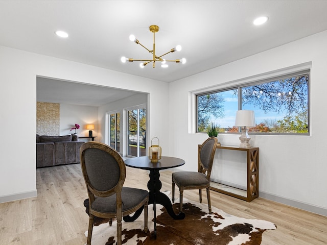 dining room featuring a notable chandelier, plenty of natural light, and light wood-type flooring